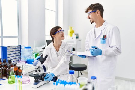 Photo for Man and woman partners wearing scientist uniform working at laboratory - Royalty Free Image