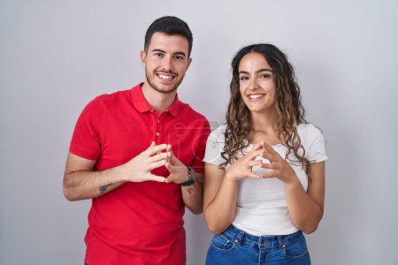 Téléchargez les photos : Young hispanic couple standing over isolated background hands together and fingers crossed smiling relaxed and cheerful. success and optimistic - en image libre de droit