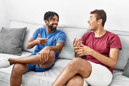 Téléchargez les photos : Two men friends having conversation sitting on sofa at home - en image libre de droit