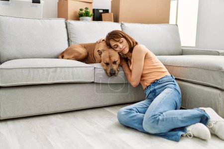 Téléchargez les photos : Young caucasian woman relaxed with hands on head sitting on floor with dog at home - en image libre de droit