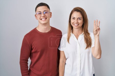 Téléchargez les photos : Mother and son standing together over isolated background showing and pointing up with fingers number three while smiling confident and happy. - en image libre de droit