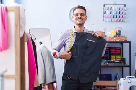 Photo for Young hispanic man tailor smiling confident holding waistcoat at tailor shop - Royalty Free Image