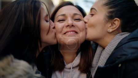 Photo for Mother and daugthers kissing and hugging each other at street - Royalty Free Image