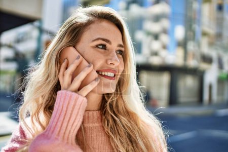Téléchargez les photos : Jeune femme blonde parlant au téléphone à la ville - en image libre de droit