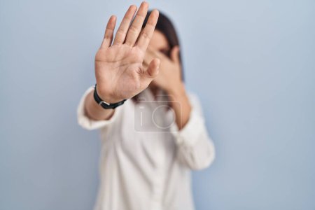 Téléchargez les photos : Jeune femme hispanique debout sur fond blanc couvrant les yeux des mains et faisant arrêter geste avec expression triste et peur. concept embarrassé et négatif. - en image libre de droit