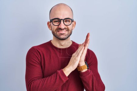 Photo for Young bald man with beard standing over white background wearing glasses clapping and applauding happy and joyful, smiling proud hands together - Royalty Free Image