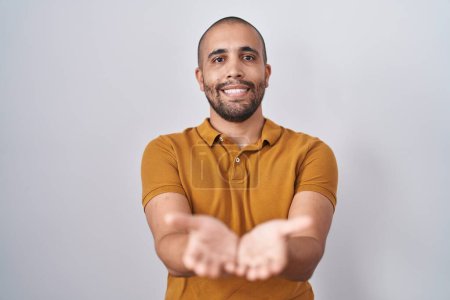 Téléchargez les photos : Hispanic man with beard standing over white background smiling with hands palms together receiving or giving gesture. hold and protection - en image libre de droit