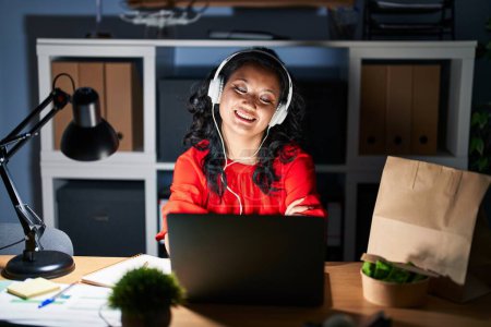 Téléchargez les photos : Jeune femme asiatique travaillant au bureau avec ordinateur portable la nuit visage heureux souriant avec les bras croisés regardant la caméra. personne positive. - en image libre de droit