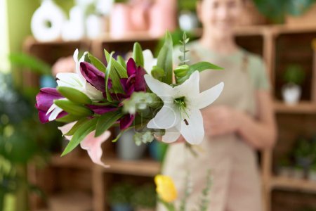 Téléchargez les photos : Jeune belle femme fleuriste tenant bouquet de fleurs à la boutique de fleurs - en image libre de droit