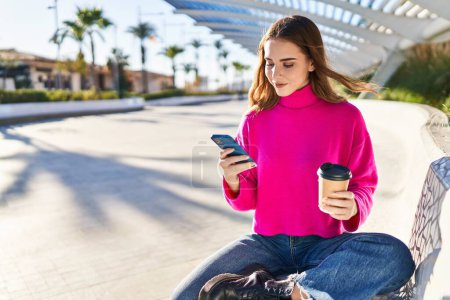 Téléchargez les photos : Young woman using smartphone drinking coffee at park - en image libre de droit