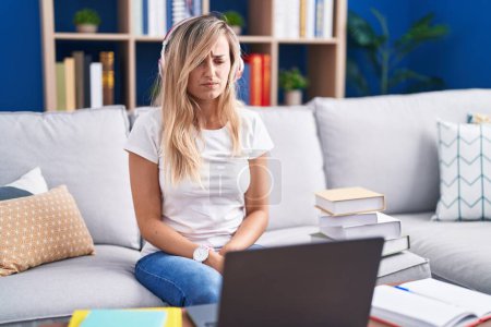 Photo for Young blonde woman studying using computer laptop at home skeptic and nervous, frowning upset because of problem. negative person. - Royalty Free Image