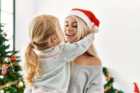 Téléchargez les photos : Mère et fille s'embrassant debout près de l'arbre de Noël à la maison - en image libre de droit