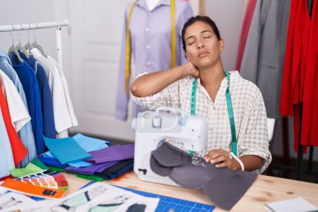 Téléchargez les photos : Jeune belle femme hispanique tailleur stressé en utilisant une machine à coudre au magasin de tailleur - en image libre de droit
