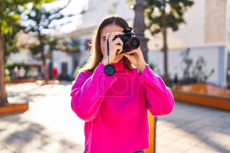 Téléchargez les photos : Jeune femme souriant confiant en utilisant une caméra professionnelle au parc - en image libre de droit