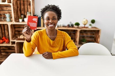 Téléchargez les photos : African american woman holding switzerland passport sitting on table at home - en image libre de droit