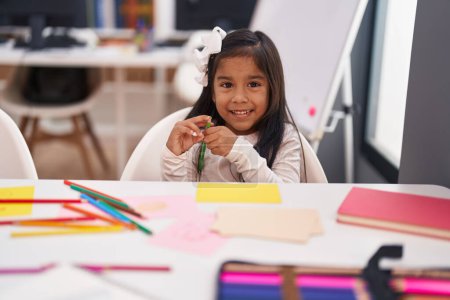 Photo for Adorable hispanic girl student smiling confident holding color pencil at classroom - Royalty Free Image
