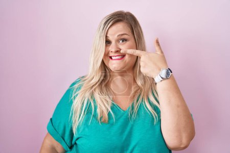Photo for Caucasian plus size woman standing over pink background pointing with hand finger to face and nose, smiling cheerful. beauty concept - Royalty Free Image