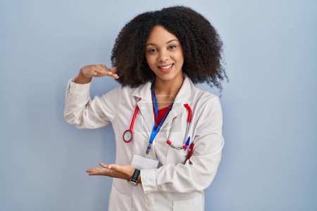Photo for Young african american woman wearing doctor uniform and stethoscope gesturing with hands showing big and large size sign, measure symbol. smiling looking at the camera. measuring concept. - Royalty Free Image