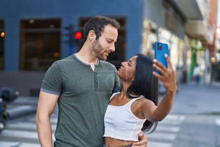 Foto de Man and woman interracial couple making selfie by smartphone at street - Imagen libre de derechos
