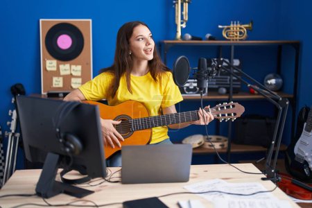 Téléchargez les photos : Young woman musician singing song playing classical guitar at music studio - en image libre de droit