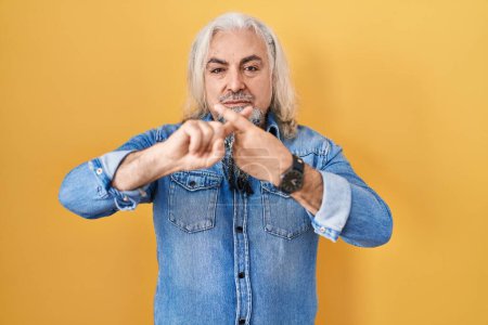 Photo for Middle age man with grey hair standing over yellow background rejection expression crossing fingers doing negative sign - Royalty Free Image