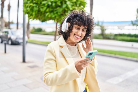 Téléchargez les photos : Young middle east woman excutive smiling confident listening to music at street - en image libre de droit
