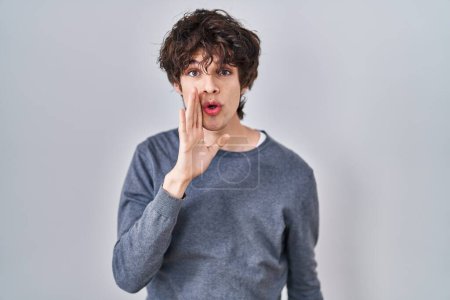 Photo for Young man standing over isolated background hand on mouth telling secret rumor, whispering malicious talk conversation - Royalty Free Image