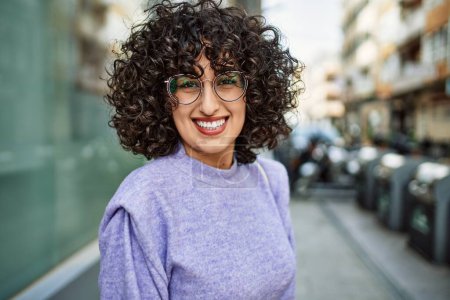 Foto de Joven mujer de Oriente Medio sonriendo confiado usando gafas en la calle - Imagen libre de derechos