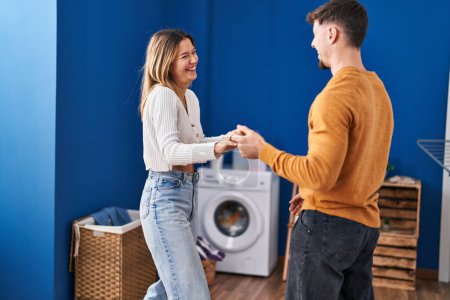 Foto de Joven pareja de hombres y mujeres sonriendo confiados bailando en la lavandería - Imagen libre de derechos