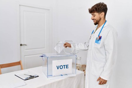 Téléchargez les photos : Young arab man wearing doctor uniform voting at electoral college - en image libre de droit
