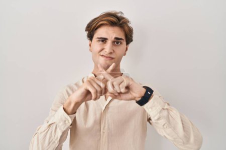 Photo for Young man standing over isolated background rejection expression crossing fingers doing negative sign - Royalty Free Image