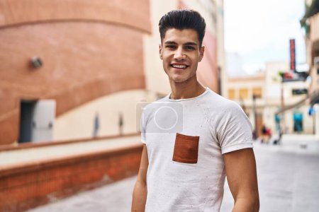 Foto de Joven hombre hispano sonriendo confiado de pie en la calle - Imagen libre de derechos