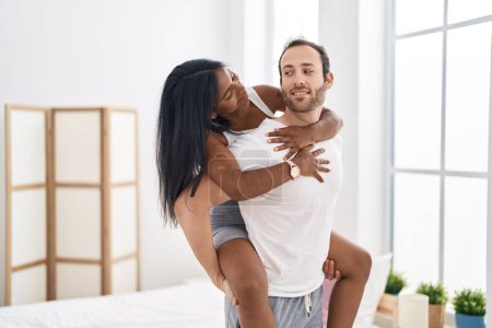 Photo for Man and woman interracial couple holding on back standing at bedroom - Royalty Free Image