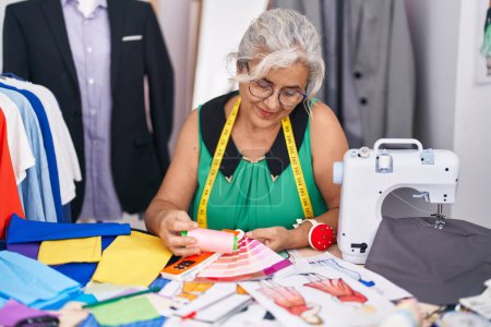 Photo for Middle age grey-haired woman tailor smiling confident holding thread and color test at tailor shop - Royalty Free Image