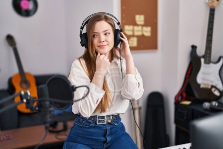 Photo for Young caucasian woman recording song at music studio serious face thinking about question with hand on chin, thoughtful about confusing idea - Royalty Free Image