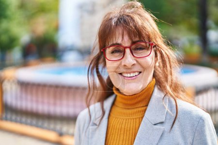 Téléchargez les photos : Femme d'âge moyen cadre d'affaires souriant confiant au parc - en image libre de droit