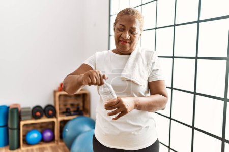 Photo for Senior african american woman smiling confident drinking water at sport center - Royalty Free Image