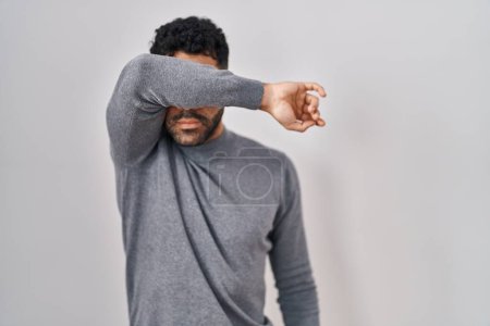 Photo for Hispanic man with beard standing over white background covering eyes with arm, looking serious and sad. sightless, hiding and rejection concept - Royalty Free Image