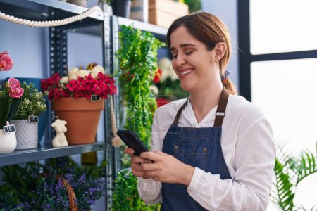 Photo for Young woman florist smiling confident using smartphone at florist shop - Royalty Free Image
