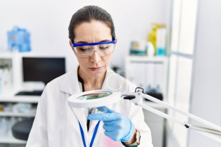 Téléchargez les photos : Jeune femme hispanique portant l'uniforme de scientifique travaillant au laboratoire - en image libre de droit