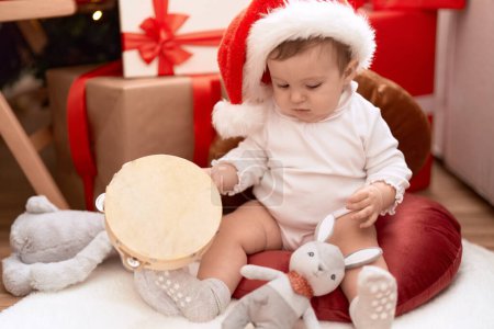 Photo for Adorable toddler holding tambourin sitting on floor by christmas gift at home - Royalty Free Image