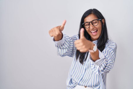 Téléchargez les photos : Jeune femme hispanique portant des lunettes approuvant faire un geste positif avec la main, pouces levés souriant et heureux pour le succès. geste gagnant. - en image libre de droit