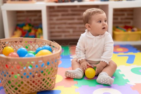 Photo for Adorable toddler playing with balls sitting on floor at kindergarten - Royalty Free Image