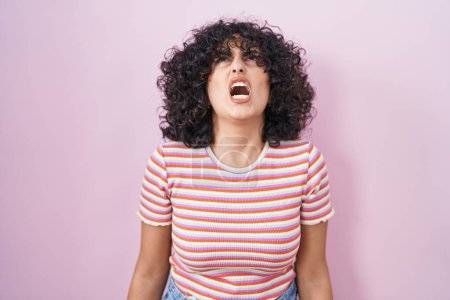 Téléchargez les photos : Young middle east woman standing over pink background angry and mad screaming frustrated and furious, shouting with anger. rage and aggressive concept. - en image libre de droit