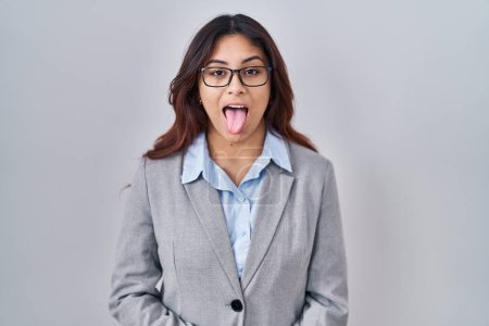 Foto de Hispanic young business woman wearing glasses sticking tongue out happy with funny expression. emotion concept. - Imagen libre de derechos