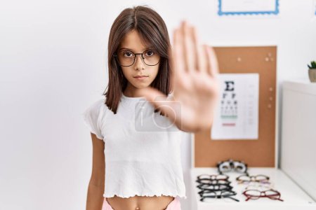 Photo for Young hispanic girl wearing glasses doing stop sing with palm of the hand. warning expression with negative and serious gesture on the face. - Royalty Free Image