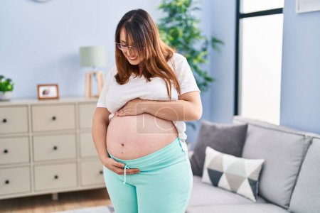 Photo for Young pregnant woman smiling confident touching belly at home - Royalty Free Image