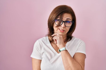 Photo for Middle age hispanic woman standing over pink background thinking worried about a question, concerned and nervous with hand on chin - Royalty Free Image