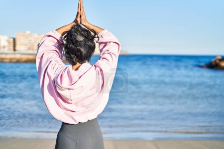 Téléchargez les photos : Jeune femme entraînement yoga exercice debout au bord de la mer - en image libre de droit