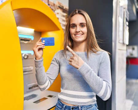 Photo for Young doctor woman holding credit card at cash point smiling happy pointing with hand and finger - Royalty Free Image